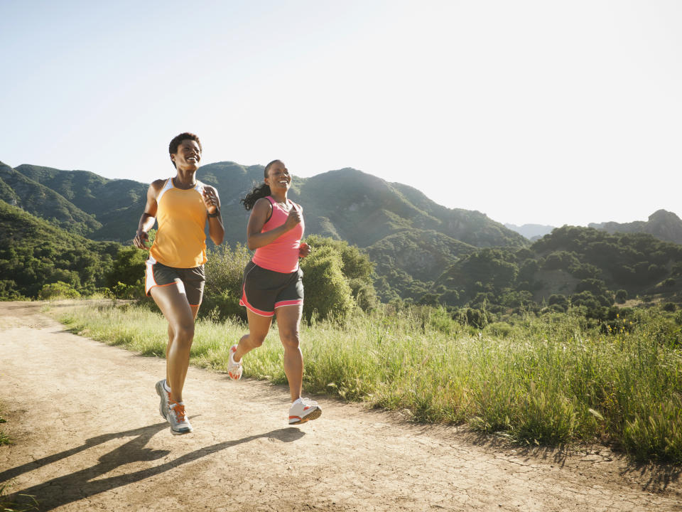 Two women running on a road with beautiful mountains in the background