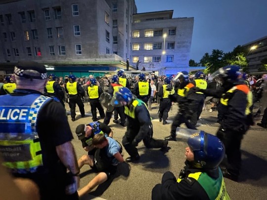 Police arrest some protesters in the distance after they tried to cross over to the side of the opposition group in Plymouth.