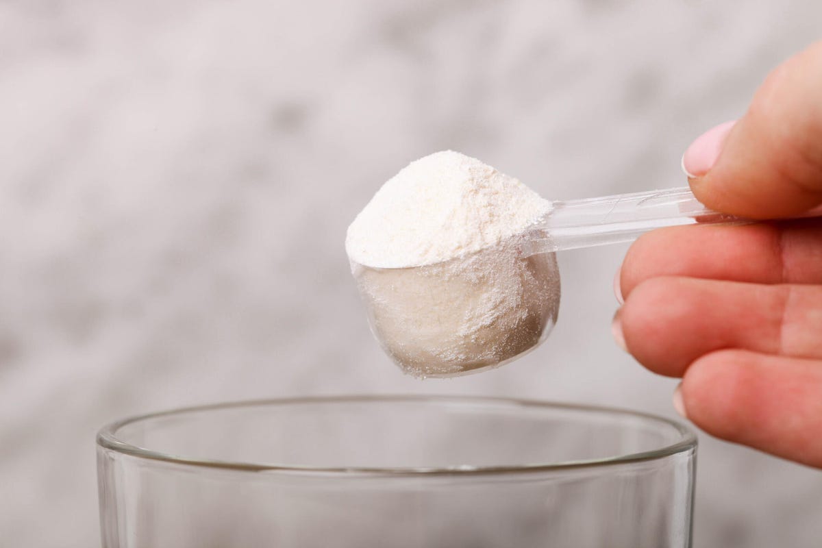 hand pours white colostrum powder